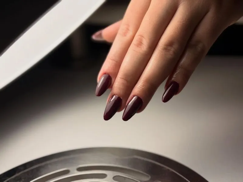 Elegáns mélybordó gél lakk manikűr arany csillámos díszítéssel, vörös selyem háttérben - Minimal Nails Mosonmagyaróvár