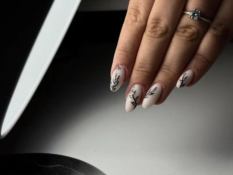 A szezon egyik legnépszerűbb mintája: tejfehér gél lakk, fekete levélkontúr és ezüst glitteres kitöltés az ujjakon. - Minimal Nails Mosonmagyaróvár